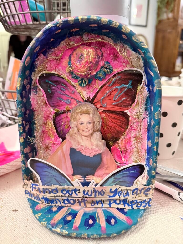 Dolly icon multi media collage with butterfly stickers, paint, tinsel and shadow box